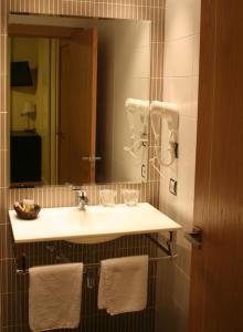 a bathroom with a sink and a mirror and towels at Hostal Restaurante La Muralla in Oña