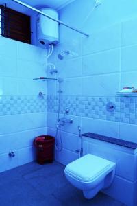 a white bathroom with a toilet and a shower at UNNATHI SUITES in Mysore
