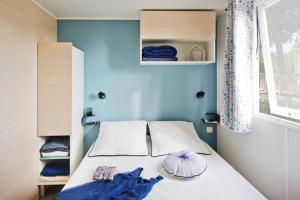 a bedroom with a bed with blue walls and a window at Camping MON CALME in Piriac-sur-Mer
