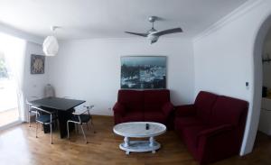 ein Wohnzimmer mit einem roten Sofa und einem Tisch in der Unterkunft D’AGOSTA Beach Apartment in Alcúdia