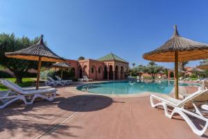 - une piscine avec 2 chaises longues et des parasols dans l'établissement Maison Ayda, à Marrakech