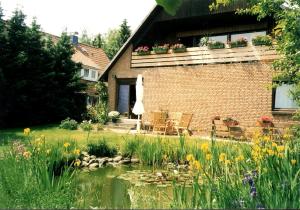 a house with a pond and flowers in the yard at Lüneburg-Melbeck, 105 qm mit Fernsicht, ruhige Sackgasse in Melbeck