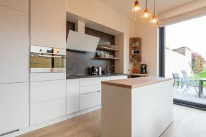 a kitchen with white cabinets and a large window at De Lokroep in Heers