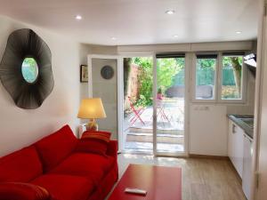 sala de estar con sofá rojo y mesa en SUITE AVEC TERRASSE ET JARDIN AUX PORTES DE PARIS, en Les Pavillons-sous-Bois