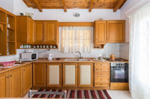 a kitchen with wooden cabinets and a sink at Villa Anna Apartments - 550m from the beach, by ZanteWize in Vasilikos