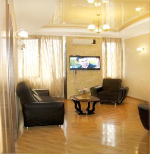 a living room with two chairs and a table and a tv at Tbilisi Comfort in Tbilisi City