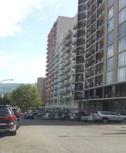 a parking lot with cars parked in front of a tall building at Tbilisi Comfort in Tbilisi City
