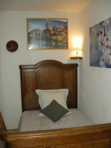 a bed with a wooden headboard and a picture on the wall at Le gîte de Gab in Eguisheim