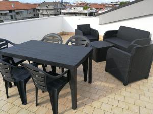 une table et des chaises noires assises sur un toit dans l'établissement La terrazza sul mare, à Silvi Marina