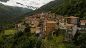 una piccola cittadina su una collina con montagne sullo sfondo di Albergo De Jean a Garzeno