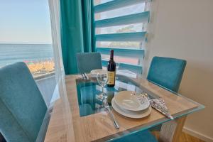 a dining room table with a bottle of wine and chairs at Hotel Obala in Dobra Voda