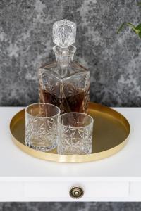 a glass bottle and two glasses on a gold tray at Zwierzyńscy Residence 2 in Pobierowo