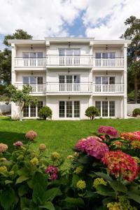 a large white building with flowers in front of it at Zwierzyńscy Residence 2 in Pobierowo