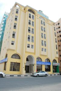 un bâtiment jaune avec des voitures garées devant lui dans l'établissement Al Buhaira Hotel Apartment, à Charjah