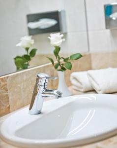 a bathroom sink with a faucet and a vase with white flowers at Hotel König in Passau