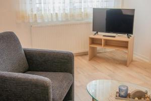 a living room with a tv and a chair and a table at Kleine-Perle in Dahme