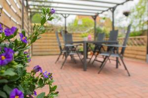 a table and chairs on a patio with purple flowers at Kleine-Perle in Dahme
