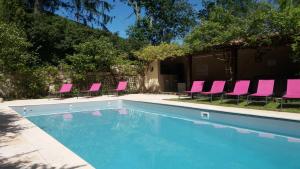 a group of pink chairs and a swimming pool at Gîtes du Hameau Baylesse in Saint-Jean-dʼAigues-Vives