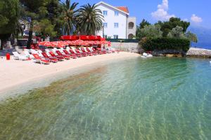 una playa con sillas y sombrillas junto al agua en Mimoza Apartments, en Ðenovići