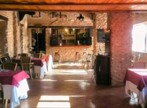 a restaurant with tables and chairs and a brick wall at Complejo El Romeral in Villanueva de los Infantes