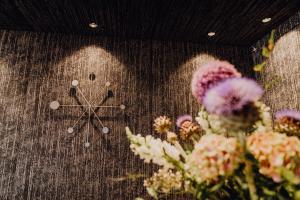Un orologio su un muro con dei fiori sopra. di Stadtvilla Schladming Boutiquehotel a Schladming