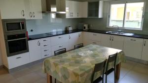 uma cozinha com armários brancos e uma mesa com cadeiras em Villa 48 em Quarteira