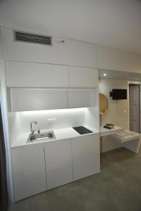 una cocina con armarios blancos y fregadero en Olive Press Hotel & Apartments, en Mithimna