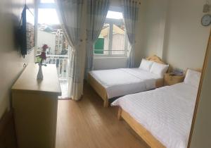 a small room with two beds and a window at CSLTDL Minh Hùng in Da Lat