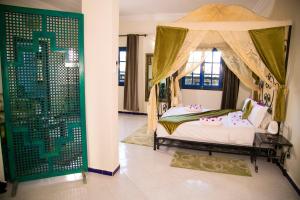 1 dormitorio con cama con dosel y almohadas rosas en Kasbah Tizimi, en Erfoud