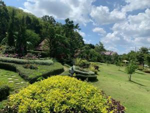 Maingern Maithong Resort في سارابوري: حديقة فيها شجيرات وزهور على حقل