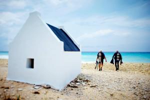 dwóch mężczyzn spacerujących po plaży ze swoimi deskami surfingowymi w obiekcie Roadrunner-Bonaire w mieście Kralendijk
