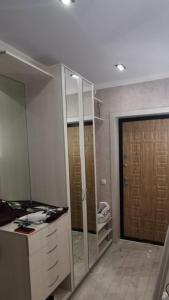 Zimmer mit einem Schreibtisch und einem Schrank mit einer Tür in der Unterkunft Уютная квартира в центре города с современным дизайном in Qostanai