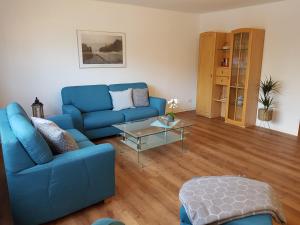 ein Wohnzimmer mit einem blauen Sofa und einem Tisch in der Unterkunft Appartementhaus Diana in Grömitz