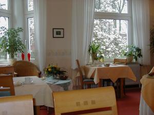 a dining room with two tables and two windows at Alleehotel-Eschen in Aurich