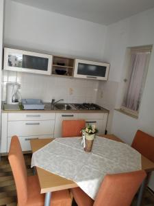 a kitchen with a table with orange chairs and a kitchen with a sink at Apartments Merica in Novalja