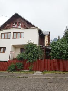 a white house with a red fence at Casa Rodica str. Clabucetului 28 in Buşteni