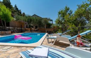 una piscina con sillas azules y blancas, una mesa y una piscina en Apartment Korina Vela Luka Gradina en Vela Luka