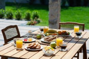 a wooden table with plates of food and glasses of orange juice at Alexandra Beach Spa Resort in Potos