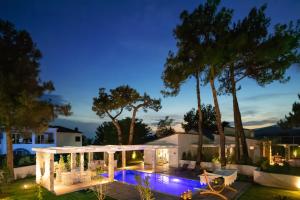 un patio trasero con piscina y árboles por la noche en Alexandra Beach Spa Resort, en Potos