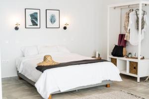 a white bedroom with a bed and a shelf with clothes at SECRET HILL in Athani