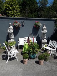 a patio with chairs and potted plants and statues at Saint Martin's Bed and Breakfast in Bandon