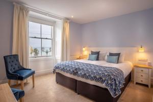 a bedroom with a bed and a chair and a window at Marazion Hotel in Marazion