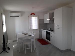 a kitchen with white cabinets and a table with a dining room at ANGOLO DI LUCE in Chioggia