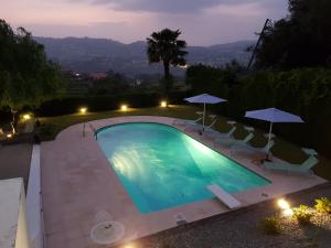 a swimming pool with chairs and umbrellas at night at Casa de Ladrido in Felgueiras