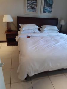 a large bed with white sheets and pillows at cocoon apartment in Victoria