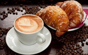 una tazza di caffè e un piatto di prodotti da forno e caffè in grani di MARGHERITA BOUTIQUE ROOMS a Margherita di Savoia