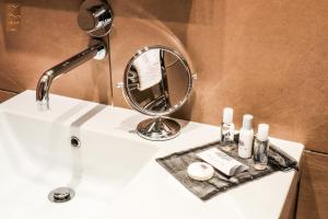 a bathroom sink with a mirror and cosmetics on it at Villa Zawaia B&B in Lagos
