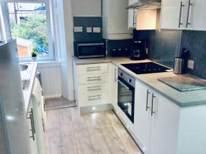 a kitchen with white cabinets and a stove top oven at THE LION'S DEN ON ROYAL STREET in Gourock