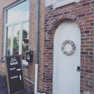 a brick building with a white door with a wreath on it at ‘t Krijtbord B&B in Alveringem
