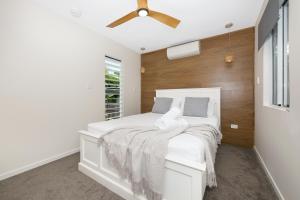 um quarto com uma cama branca e uma ventoinha de tecto em Cosy 2 bedroom home em Townsville